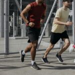 Energetic group of people running together outdoors under bright sunlight, wearing comfortable sportswear.